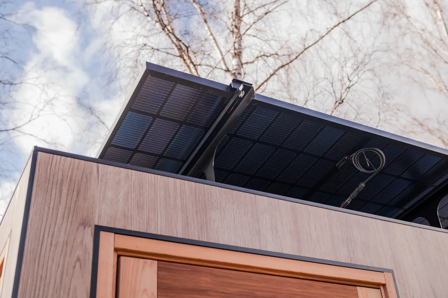 Solar panel on a sauna with trees and sky in the background