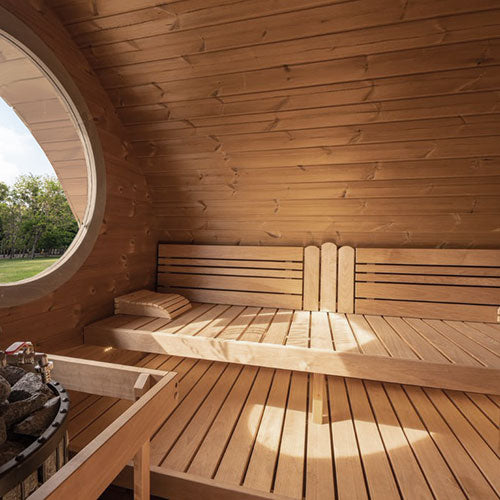 Wooden sauna interior with benches and a circular window.