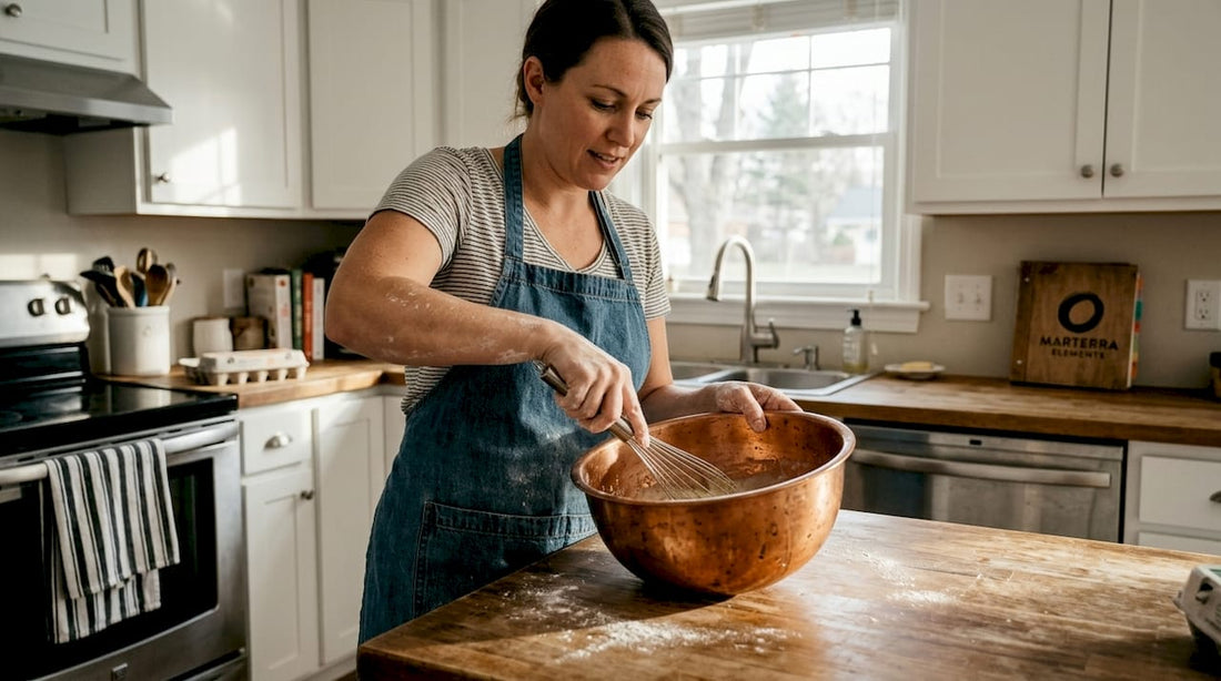 Baker whisking egg whites in copper bowl