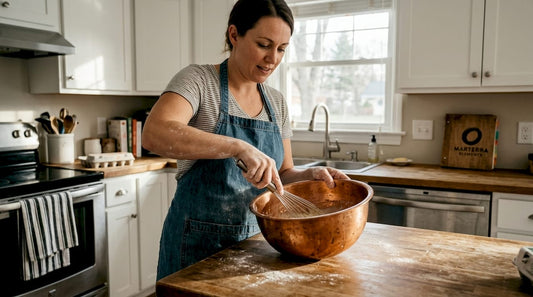 Baker whisking egg whites in copper bowl