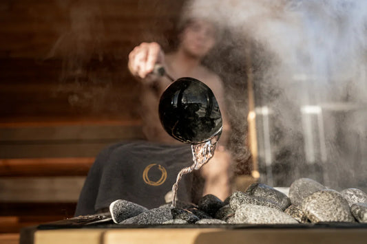 Man throwing water on sauna rocks