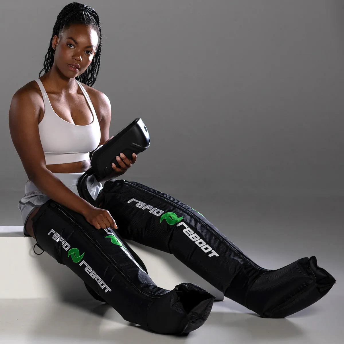 Woman using compression boots with 'Rapid Reboot' branding on a gray background