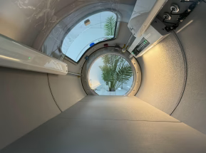 Circular tunnel - inside hyperbaric chamber, with a view of a tree at the end