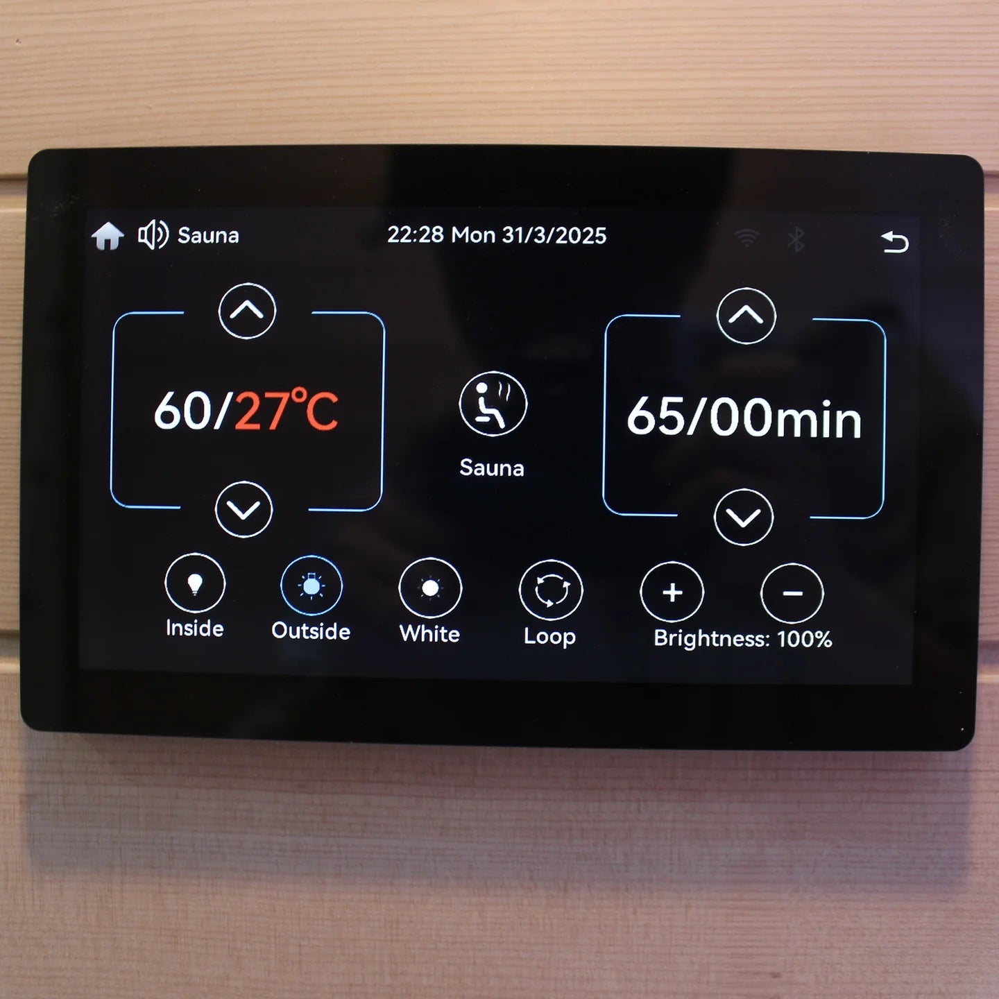 Digital display panel for a sauna with temperature and time settings on a wooden background