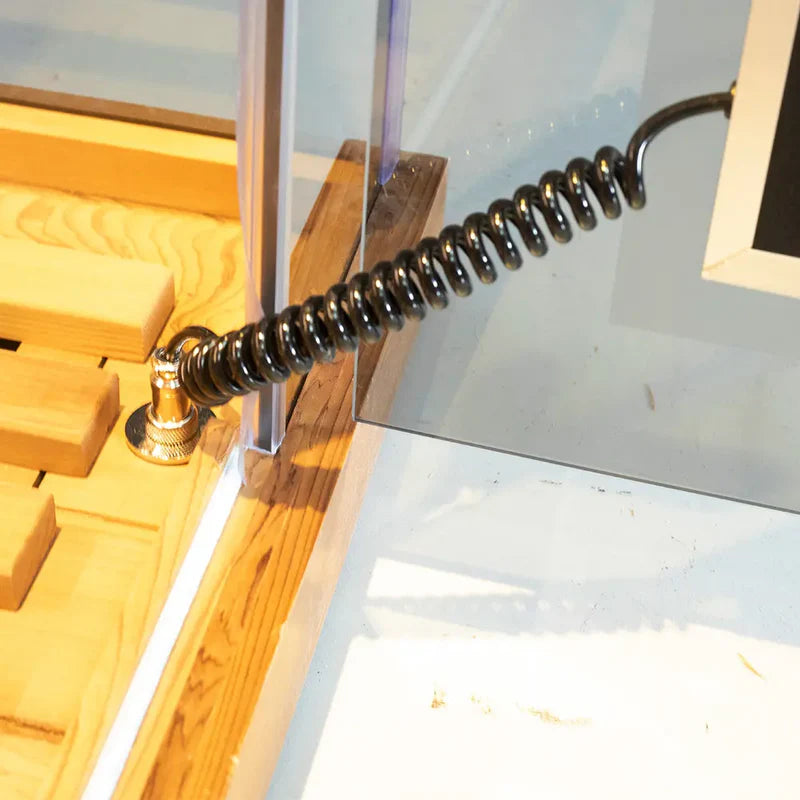 Coiled black cable attached to a metallic surface with wooden blocks in the background
