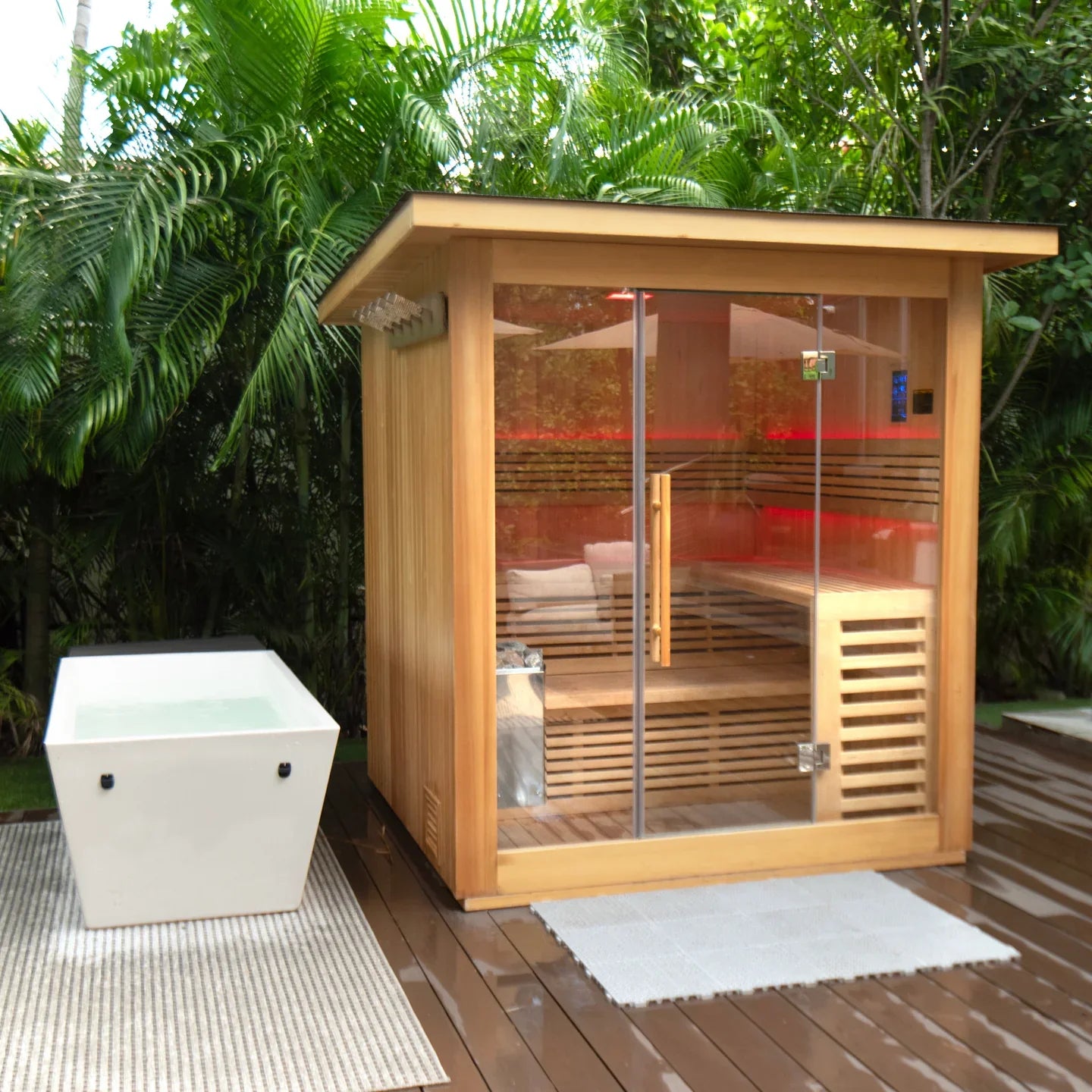 Wooden outdoor sauna with glass door on a wooden deck surrounded by greenery