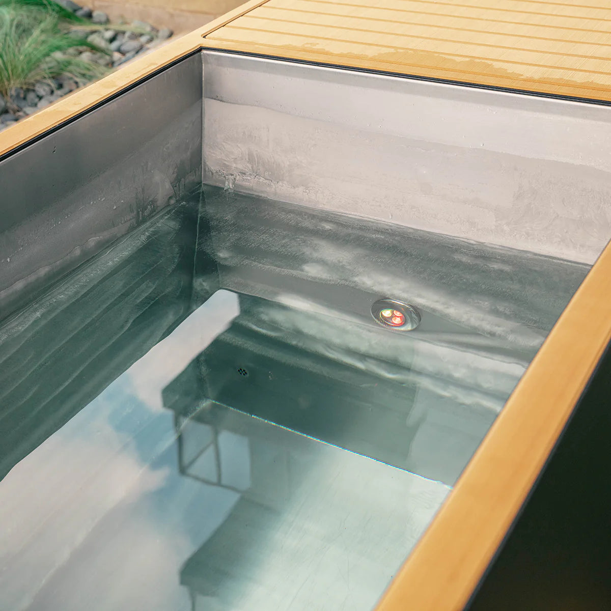 Small outdoor hot tub with wooden lid and water inside