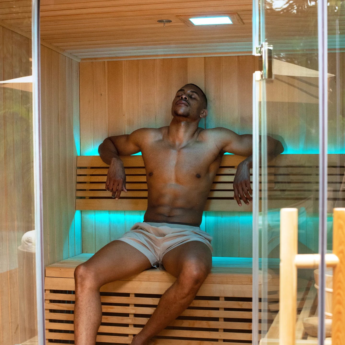 Man relaxing in a wooden sauna with blue lighting