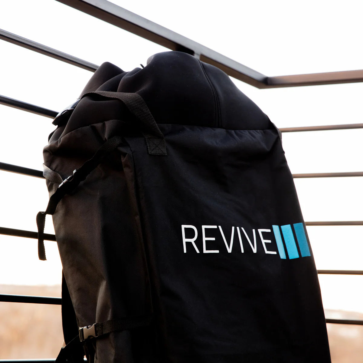 Black backpack with 'REVIVE' logo on a metal railing background