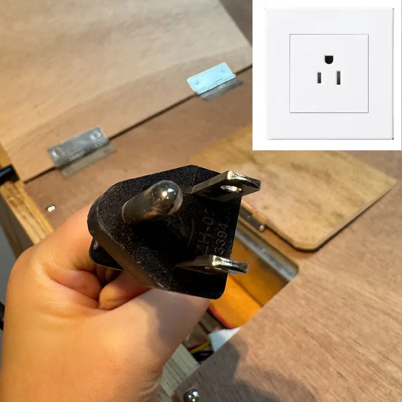 Hand holding a plug with an inset showing a power outlet on a wooden surface.