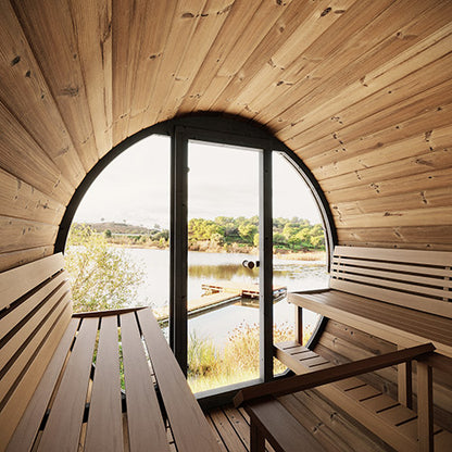 Wooden sauna with large round window overlooking a lake and trees