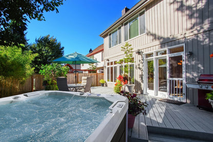Outdoor hot tub in a backyard with a house and deck in the background