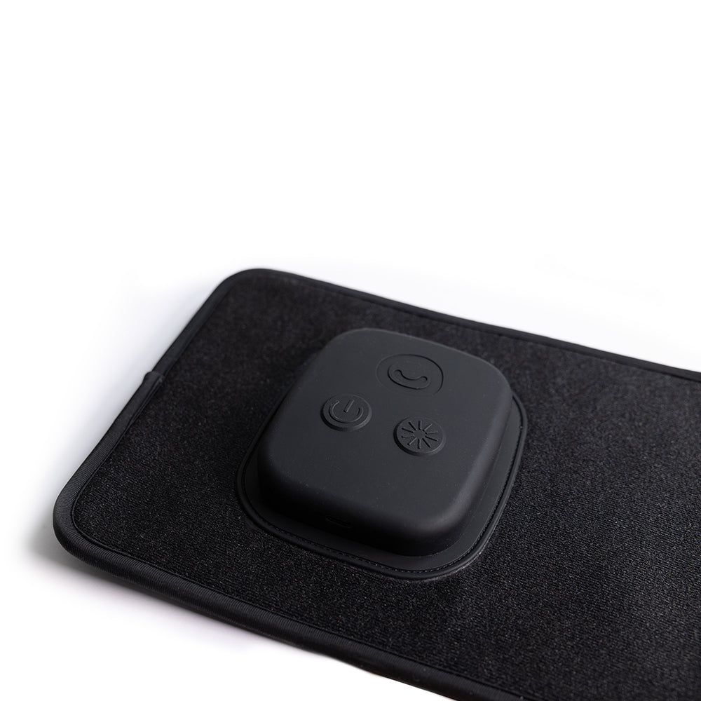 Black electronic device with buttons on a black mat against a white background