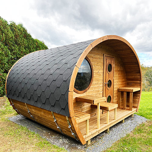 Wooden barrel-shaped cabin with a roof in an outdoor setting