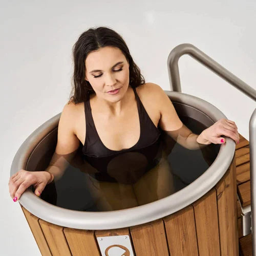Woman sitting in a wooden cold plunge with a white background