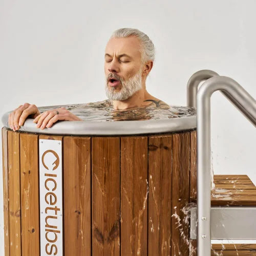 Man with closed eyes leaning over a wooden cold plunge with 'Icetubs' branding.