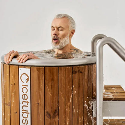 Man with closed eyes leaning over a wooden cold plunge with 'Icetubs' branding.