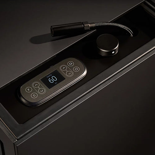 Black temperature controler with digital display and keypad on a dark surface