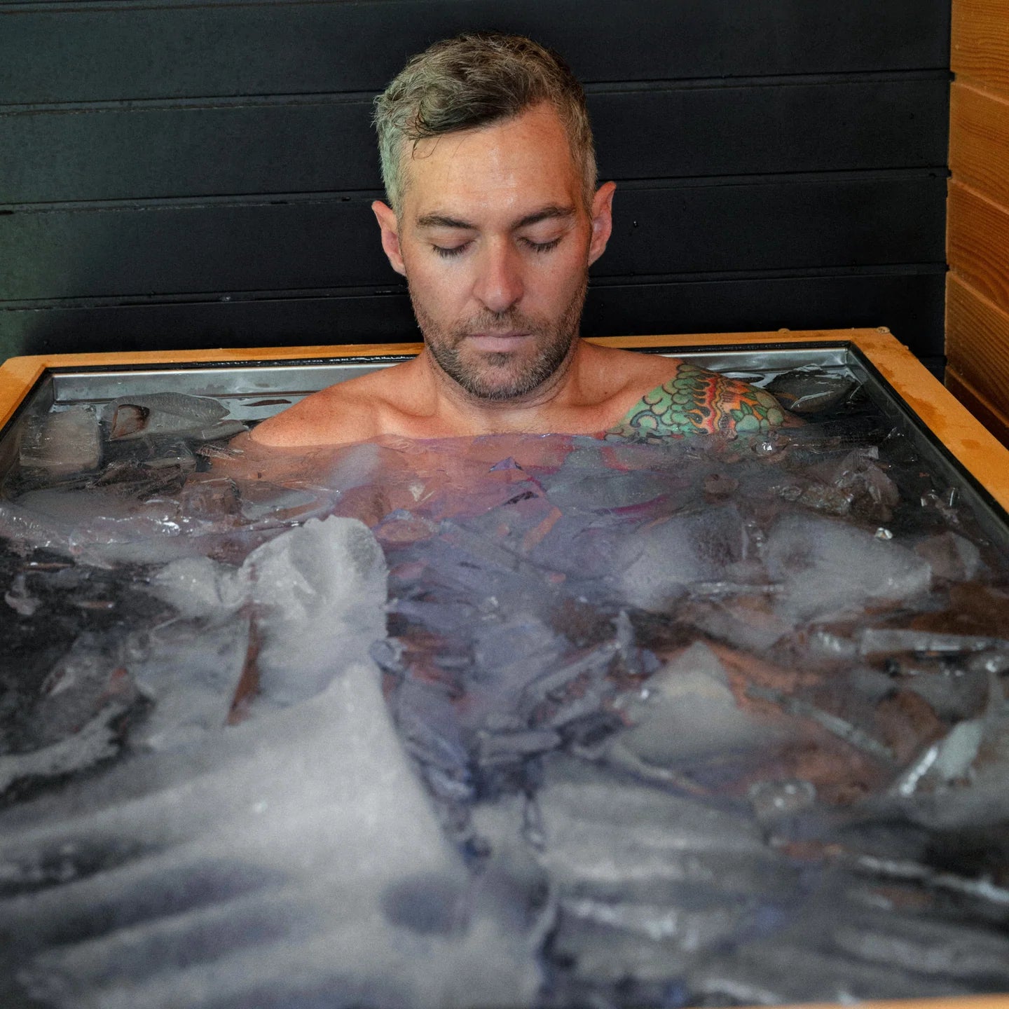 Man in an ice bath with a dark background