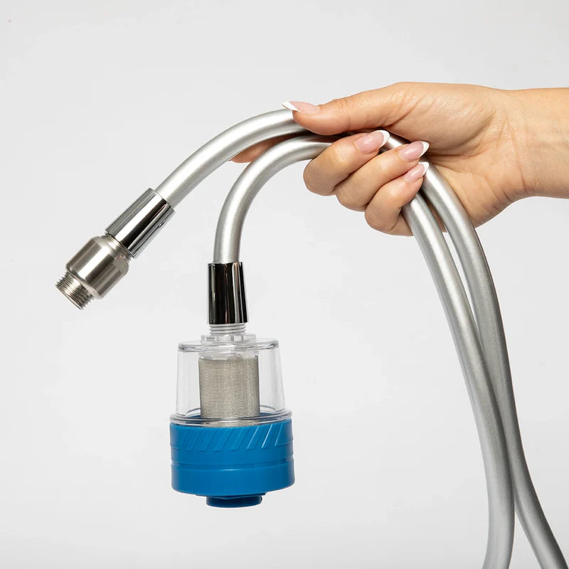 Hand holding a kitchen faucet filter with a clear hose on a light gray background