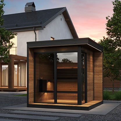 Modern wooden sauna with glass doors in front of a house during sunset.