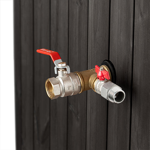 Brass valve with red handles attached to a black metal surface
