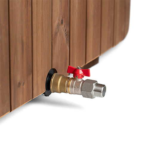 Brass outdoor faucet with red handles attached to a wooden wall.