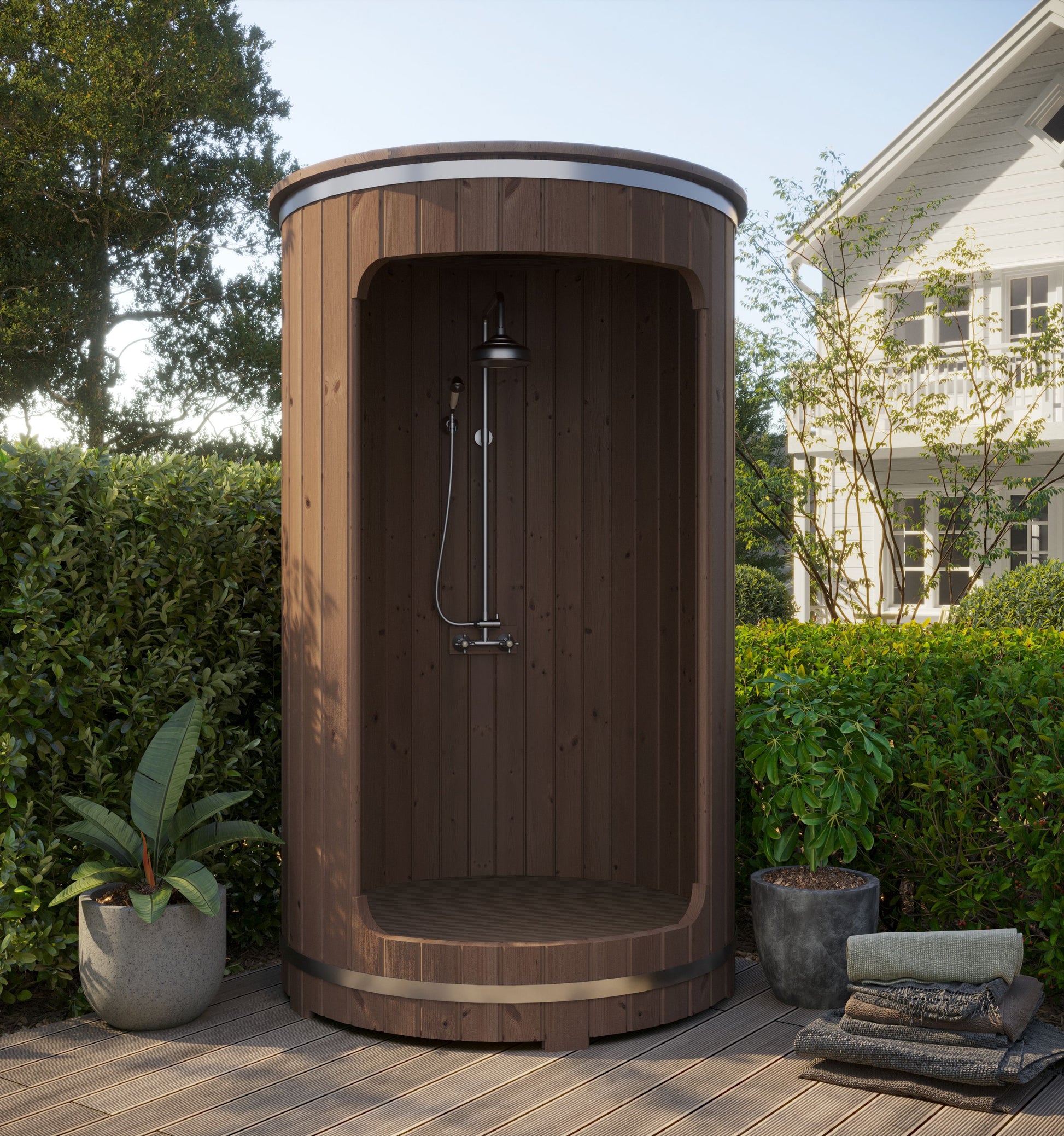 Wooden outdoor shower enclosure with plants and towels on a patio