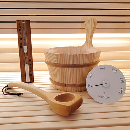 Wooden sauna bucket, ladle, and thermometer on a wooden surface with a blurred background