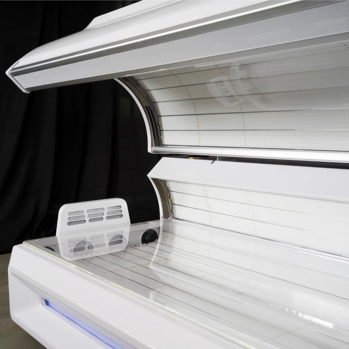 Close-up of a white red light bed with a black curtain in the background