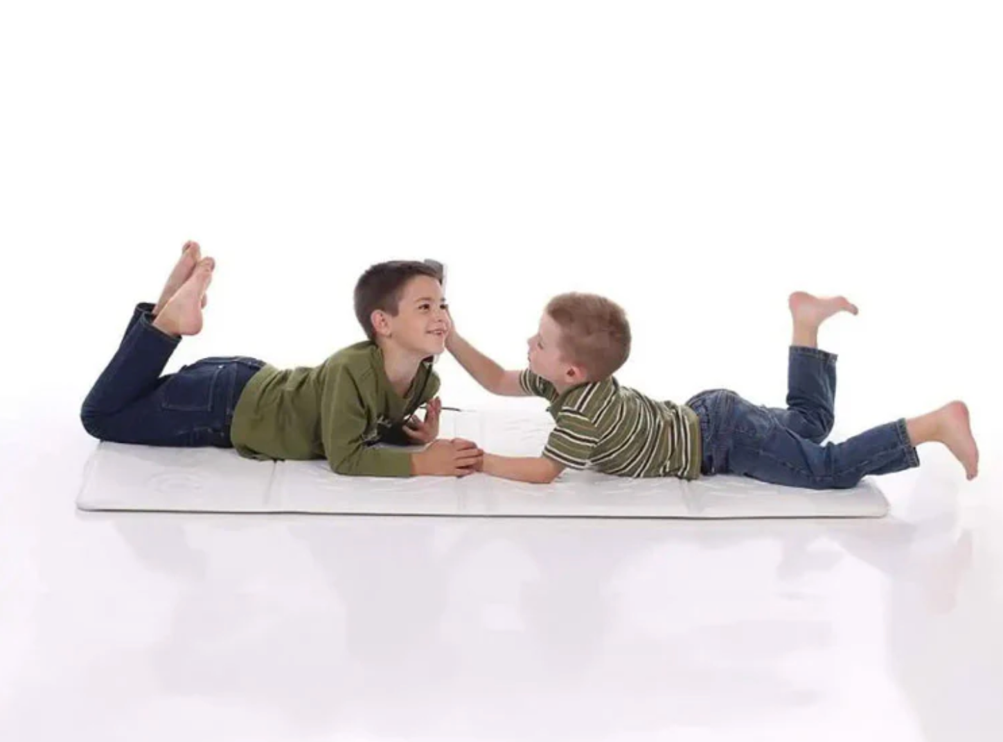 Two children playing on a white mat against a white background