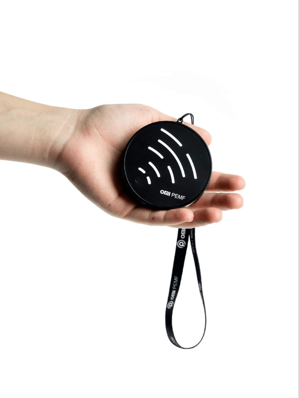 Hand holding a black circular pemf device with a strap on a white background