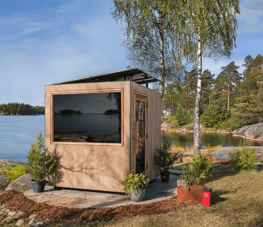 Modular sauna by a lake with trees and water in the background