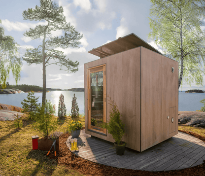 Wooden sauna by a lakeside with trees and a clear sky