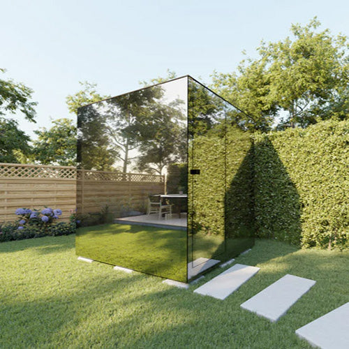 Reflective outdoor glass sauna in a garden setting with trees and a wooden fence