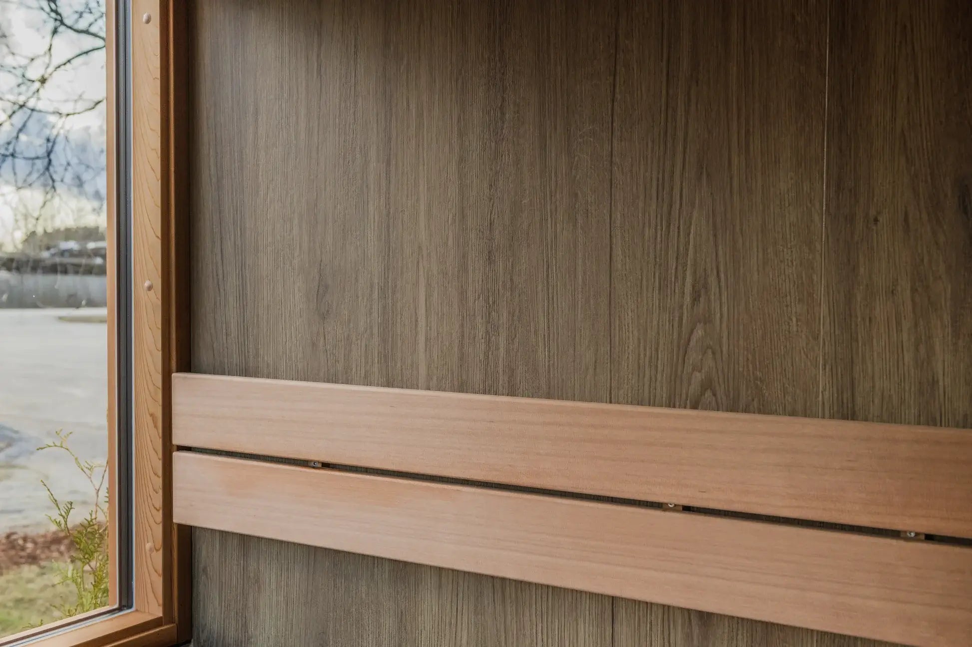 Wooden window frame and panel on a wooden wall with a blurred outdoor background