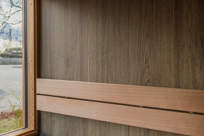 Wooden window frame and panel on a wooden wall with a blurred outdoor background