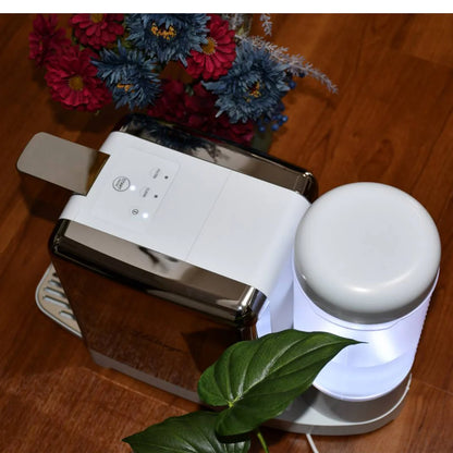 White electronic device with a lamp on a wooden surface with flowers and leaves.