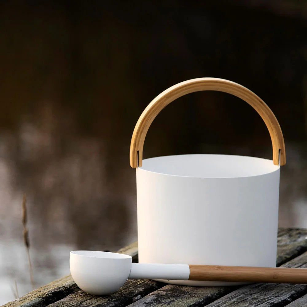 white bucket with wooden handle and ladle on a wooden bench