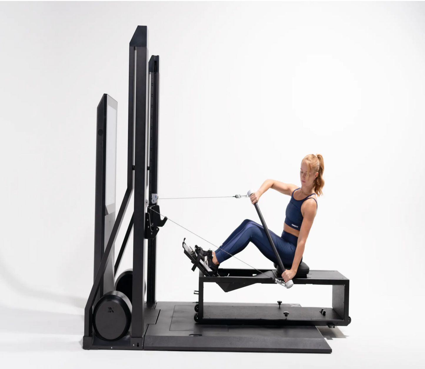 Woman using a reformer machine on a white background