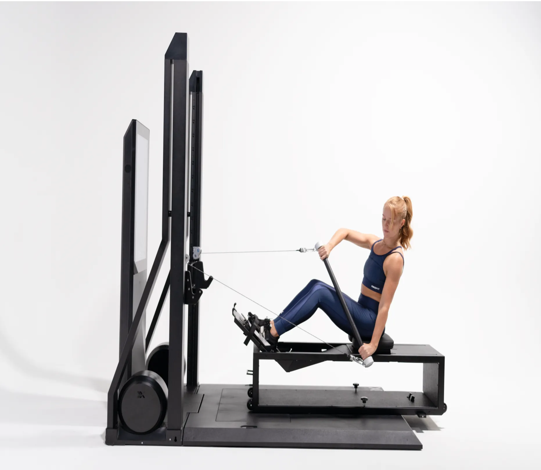 Woman using a reformer machine on a white background