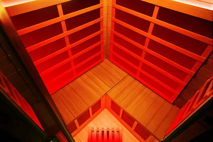 Infrared sauna with red interior panels and wooden floor.