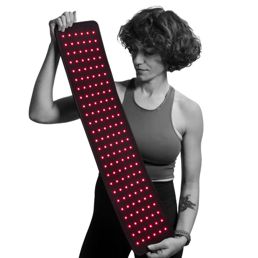 Person holding a long, rectangular red light device with red LED lights on a white background