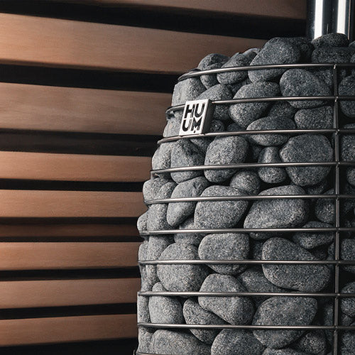 Decorative stone wall with metal grid and 'HUUM' logo against a wooden slat background