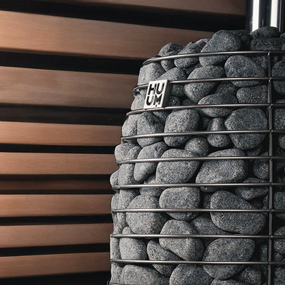Decorative stone wall with metal grid and 'HUUM' logo against a wooden slat background