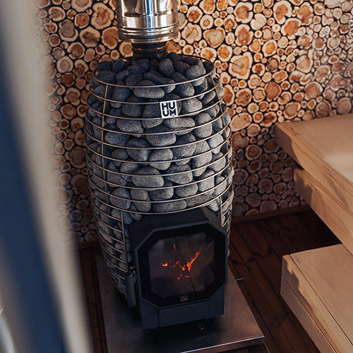 Stacked stone wood stove with glowing embers against a wooden wall.
