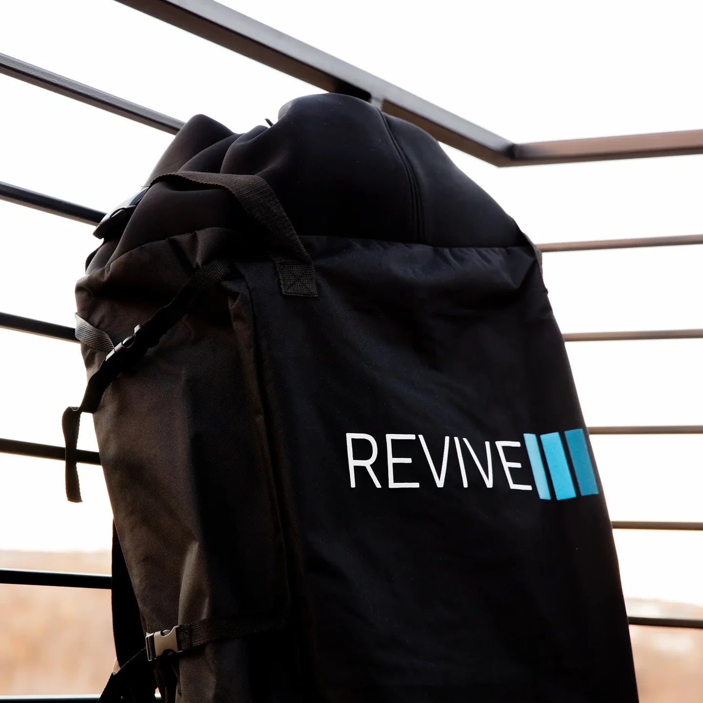 Black backpack with 'REVIVE' logo on a metal railing background