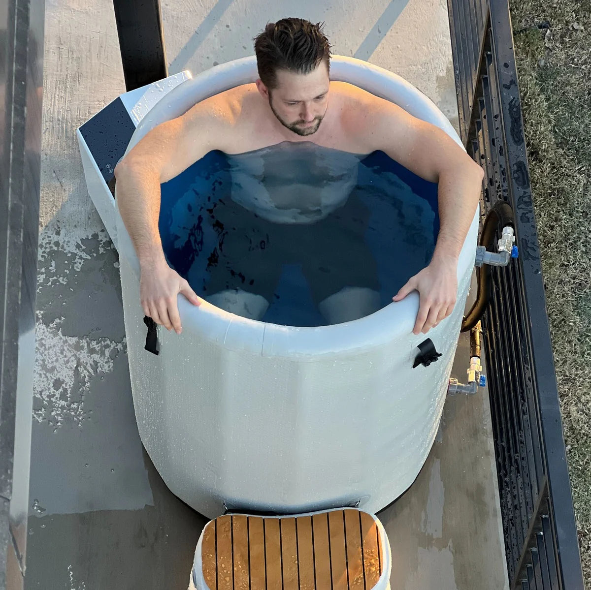 Man sitting in a portable Cold tub  on a wooden deck.
