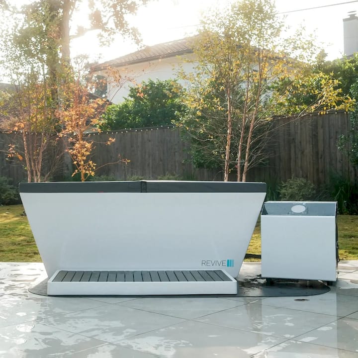 Outdoor setting with a large white and gray Cold tub  and a chiller on a tiled patio.