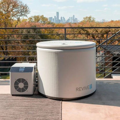 Cold tub with 'REVIVE' branding on a rooftop with a city skyline in the background.